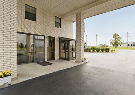 a brick building with a large empty parking lot at American Inn - Paducah in Paducah