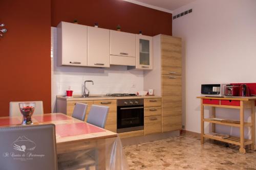 una cocina con armarios blancos y una mesa con sillas. en Il Canto di Partenope, en Nápoles