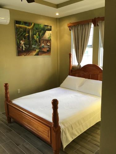 a bedroom with a wooden bed with white sheets at Hidden Treasure Vacation Home Bay Blue Suite 2 in Belize City