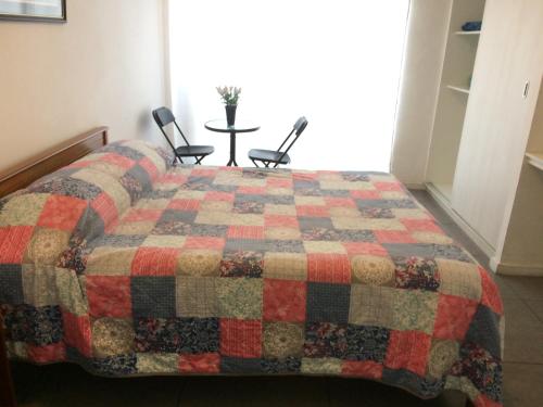 1 dormitorio con edredón en una cama con 2 sillas en Hospedaje Amunátegui, en Iquique