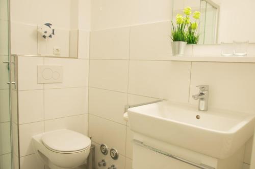 a white bathroom with a toilet and a sink at Haus am Deich Wohnung 11 in Dahme
