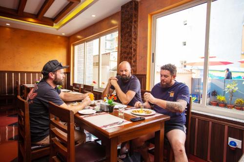 three men sitting at a table in a restaurant at Hotel Iceland in Pokhara