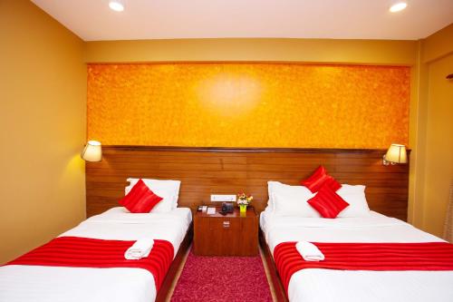 two beds in a hotel room with red pillows at Hotel Iceland in Pokhara
