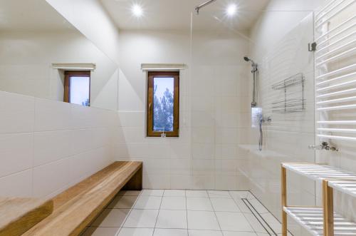 a white bathroom with a shower and a bench at Domki nad Jeziorem in Rajgród