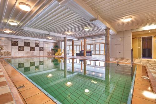 a swimming pool with a green floor in a building at Hotel der Bäume in Drachselsried