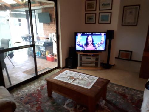a living room with a tv and a coffee table at Comfortable Secure Homeshare in Perth