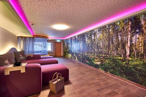 a living room with a large wall mural of trees at Hotel der Bäume in Drachselsried