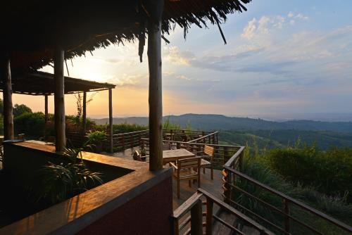 a restaurant with tables and chairs and a view of the mountains at Isunga Lodge in Kibale Forest National Park