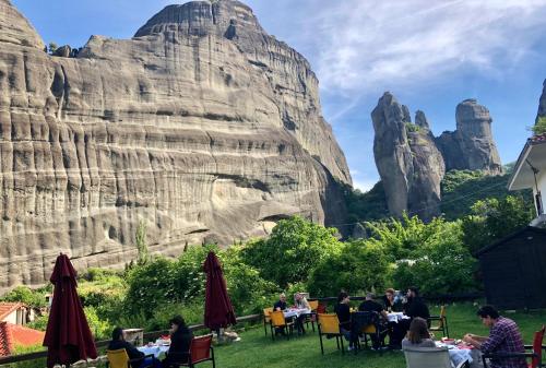 people sitting at tables in front of a rock formation at Archontiko Mesohori Meteora in Kalabaka