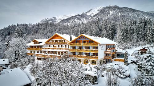 a building covered in snow in front of a mountain at Romantik Alpenhotel Waxenstein in Grainau