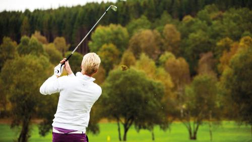 a man swinging a golf club in a field at Villa Pernilla in Orkelljunga