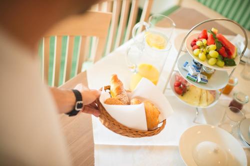 a person holding a basket of bread and a bowl of fruit at Apartmenthotel Ritterhof Suites & Breakfast in Schenna