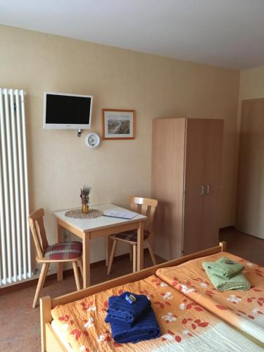 ein Schlafzimmer mit einem Tisch und einem Schreibtisch mit einem TV in der Unterkunft Pension Hönel-Hof Bad Schandau in Bad Schandau