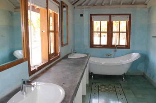 a bathroom with two sinks and a bath tub and a tubermottermott at Desa Limasan Resort in Kalak