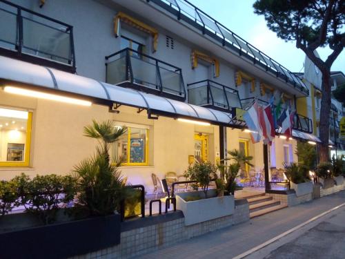 a building with chairs and plants in front of it at Hotel Marzia con Piscina in Riccione