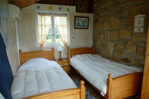 two beds in a room with a stone wall at Natursteinhaus in Portsall in Ploudalmézeau