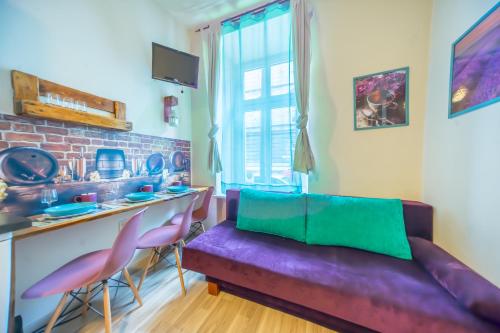 a living room with a purple couch and pink chairs at Apartamenty Idylla in Krakow