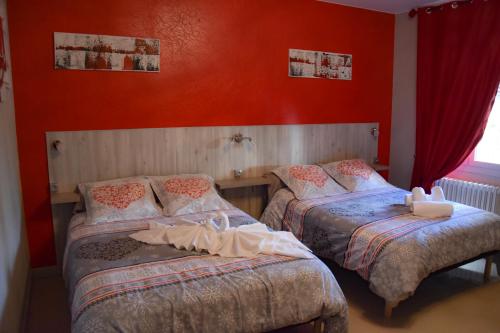 two beds in a room with red walls at Hotel des Remparts in Villeneuve-sur-Lot