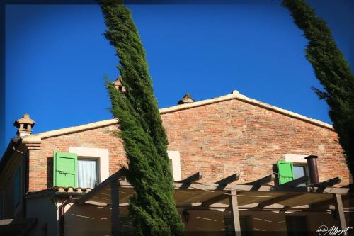 a building with green shutters and a tall tree at Le Maraclà Country House in Iesi