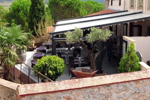 eine Außenterrasse mit Tischen, Stühlen und Bäumen in der Unterkunft Auberge du Cellier in Montner