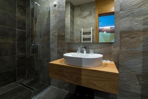 a bathroom with a sink and a shower and a mirror at Hotel Safir in Bihać