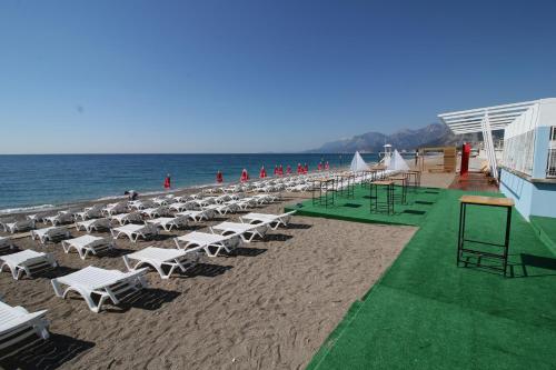 a beach with white lounge chairs and the ocean at Güden-Pearl in Antalya