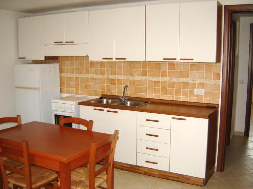 a kitchen with white cabinets and a table and a sink at Casa Liliana in Oristano