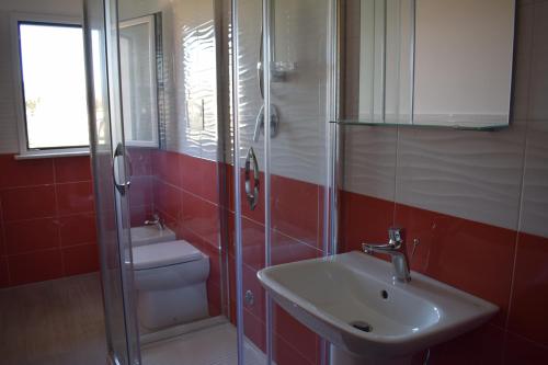 y baño con lavabo, ducha y aseo. en Eclisse House - close to the beach, en Villaggio San Leonardo