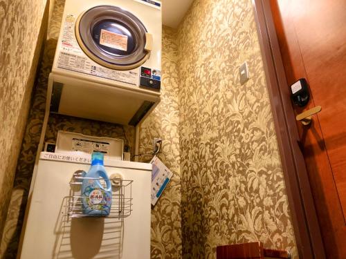a small bathroom with a refrigerator with a bottle on it at Hotel Coco Grand Kitasenju in Tokyo