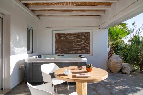 a patio with a table and chairs and a tub at Ornos Blue in Ornos