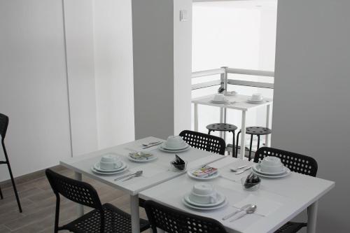 a white table with chairs and dishes on it at Residencial Tropicália AL in Praia da Barra