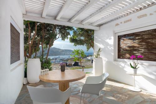a patio with a table and chairs and a large window at Ornos Blue in Ornos
