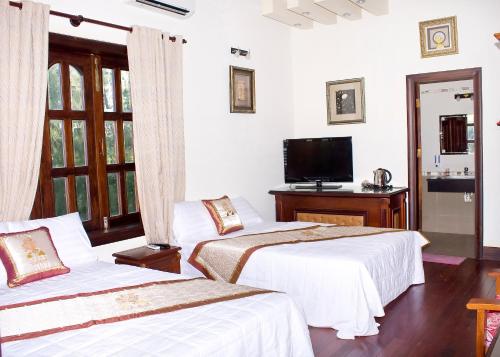 sypialnia z 2 łóżkami i telewizorem w obiekcie Gold Rooster Resort w mieście Phan Rang-Tháp Chàm