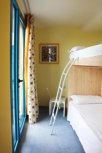 a room with a bunk bed and a ladder next to a window at Hotel Cristallo in Lignano Sabbiadoro