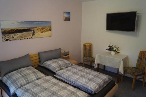 a room with two beds and a table and a tv at Ferienwohnung Familie Neugebauer in Bruchhausen-Vilsen