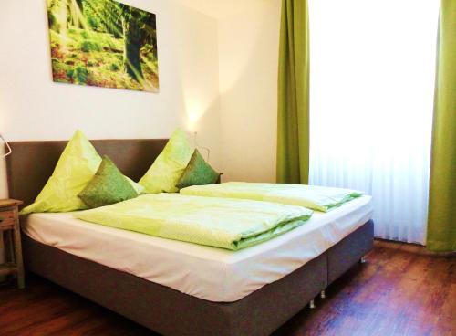 ein Bett mit grünen und gelben Kissen in einem Zimmer in der Unterkunft Ferienwohnung 14 - Sofia Haus Hühnergott in Ostseebad Sellin