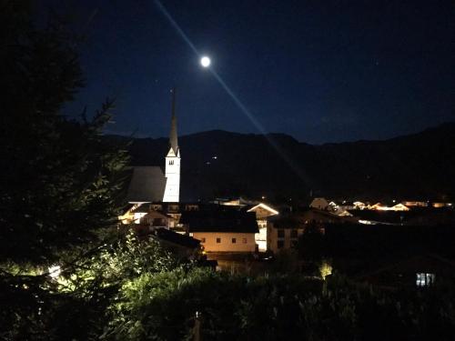 a white church with a steeple at night with the moon at VILLA OXA - Boutique Design Hotel in Maria Alm am Steinernen Meer
