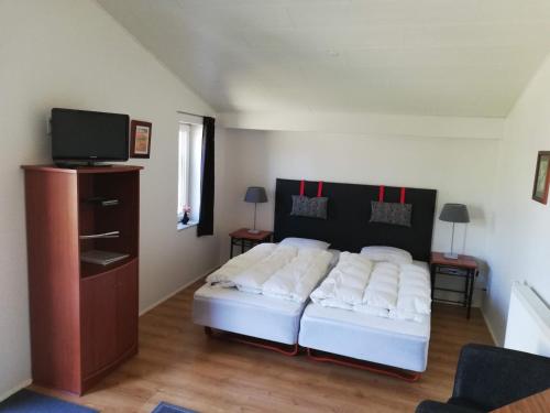 a bedroom with a bed with white pillows and a tv at Bindesbølgård Farm Holiday in Give