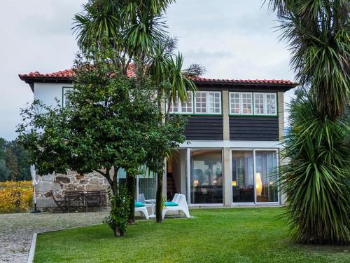 a house with palm trees in front of it at Casa da Vinha in Arcos de Valdevez