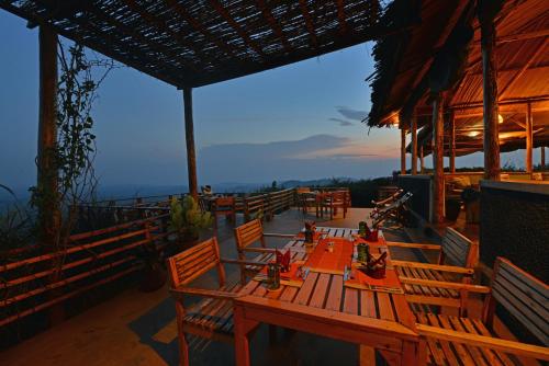 a restaurant with wooden tables and chairs on a roof at Isunga Lodge in Kibale Forest National Park