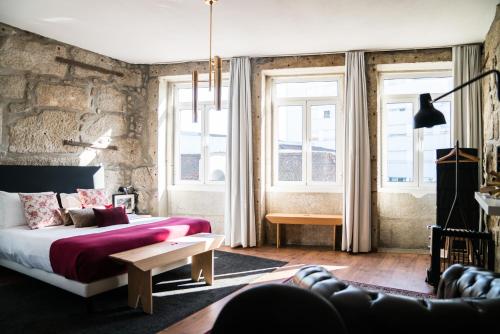 - une chambre avec un lit et un mur en pierre dans l'établissement Downtown Residence by Apartments2Enjoy, à Porto