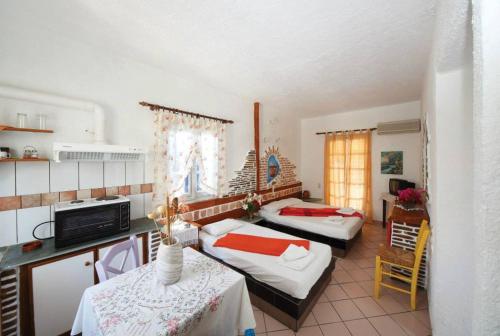 una camera con due letti e una cucina con tavoli di Aposperitis Rooms & Apartments a Kinion
