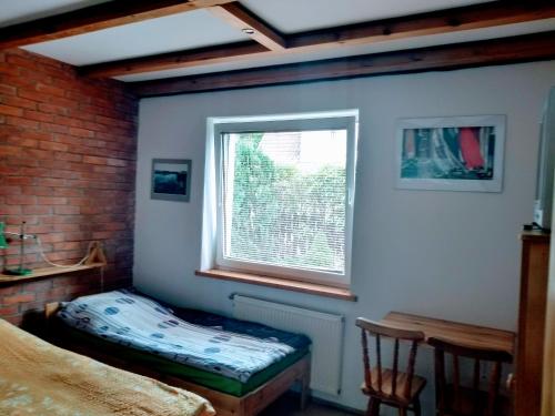 a bedroom with a window and a bed and a table at Pensjonacik Gafel in Ruciane-Nida