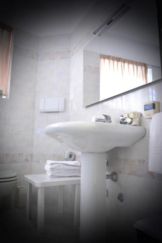 a white bathroom with a sink and a mirror at Hotel Pinamonte in Costermano sul Garda