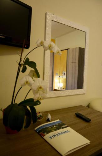 a desk with a mirror and a vase with white flowers at Hotel Pinamonte in Costermano sul Garda