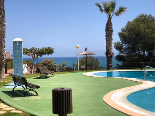 Cabo Roig - Blue Luxury Apartment في كابو رويج: مسبح و كرسيين و نخلة و المحيط