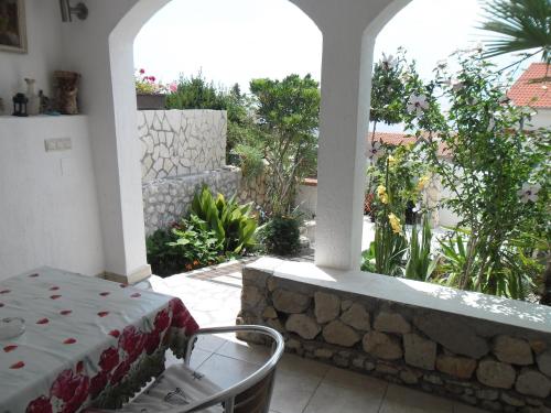 a patio with a table and a stone wall at Mirta in Stara Baška