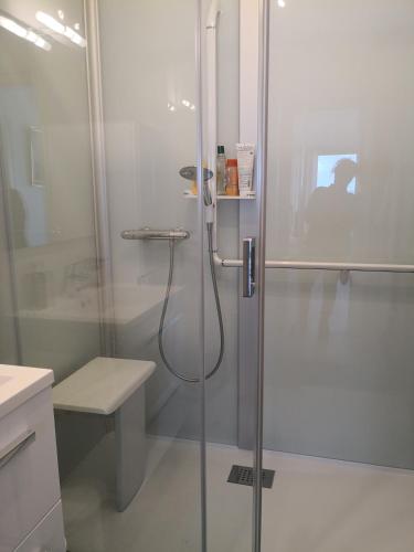 une douche avec une porte vitrée dans une salle de bain dans l'établissement Le Splendid, à La Baule