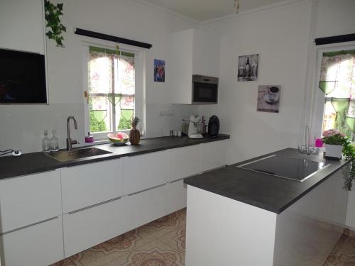 een keuken met witte kasten en zwarte aanrechtbladen bij Lifestyle Balaton in Siófok