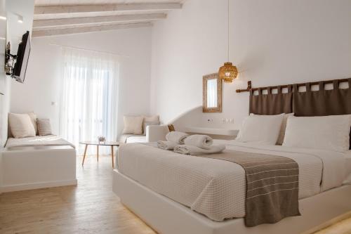 a white bedroom with a large bed and a couch at Blue Bay Resort Village in Batsi